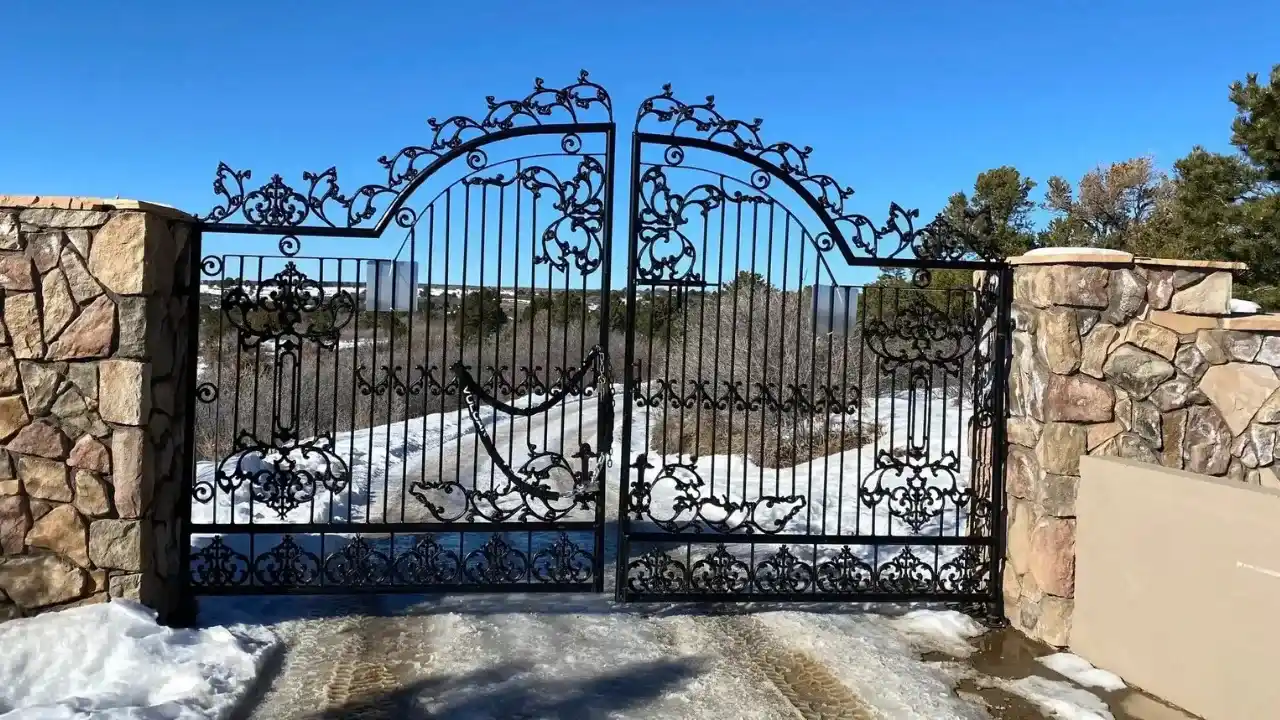 Ornate decorative metal gate with stone pillars and intricate scrollwork