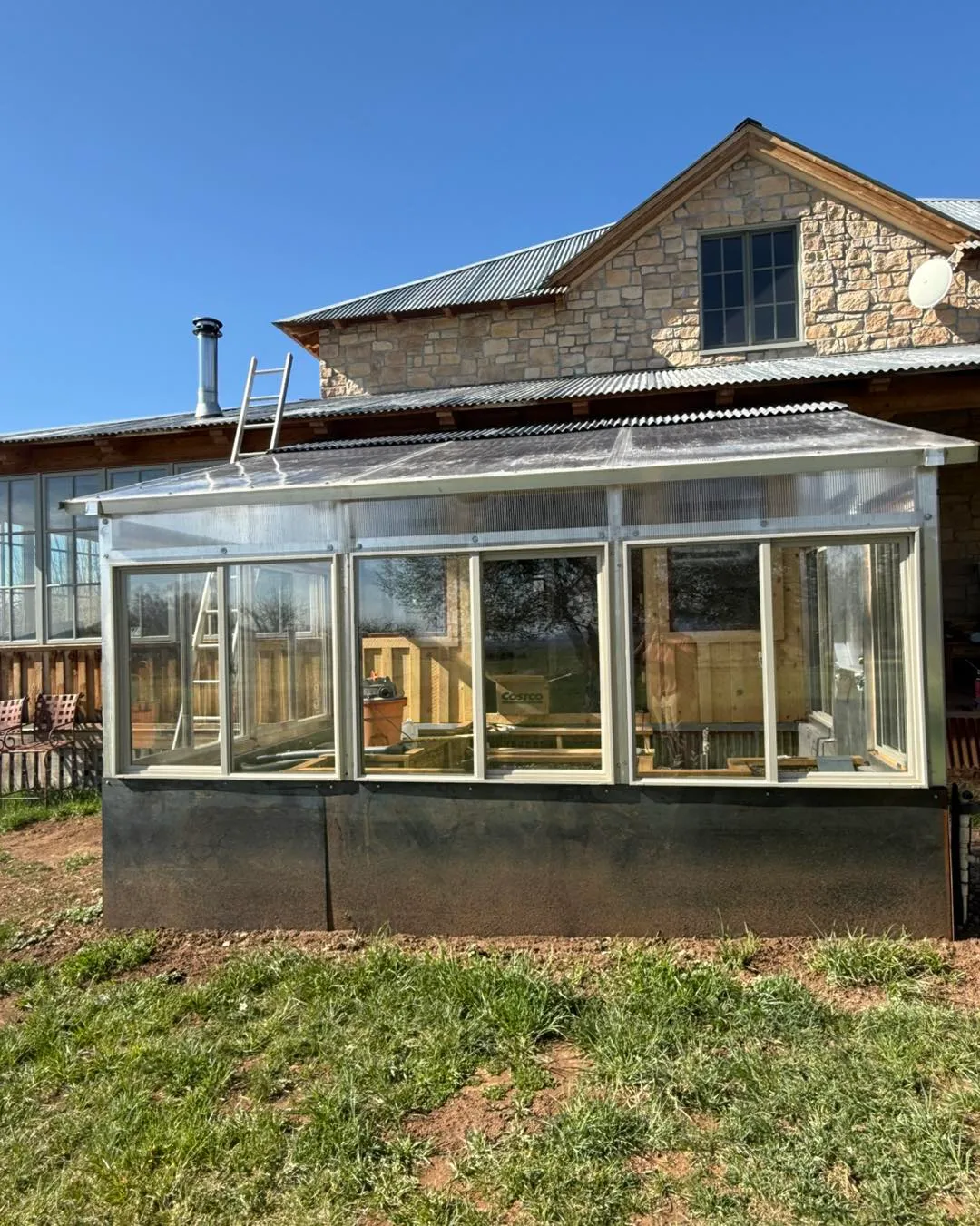 Large greenhouse structure with metal framework attached to stone building