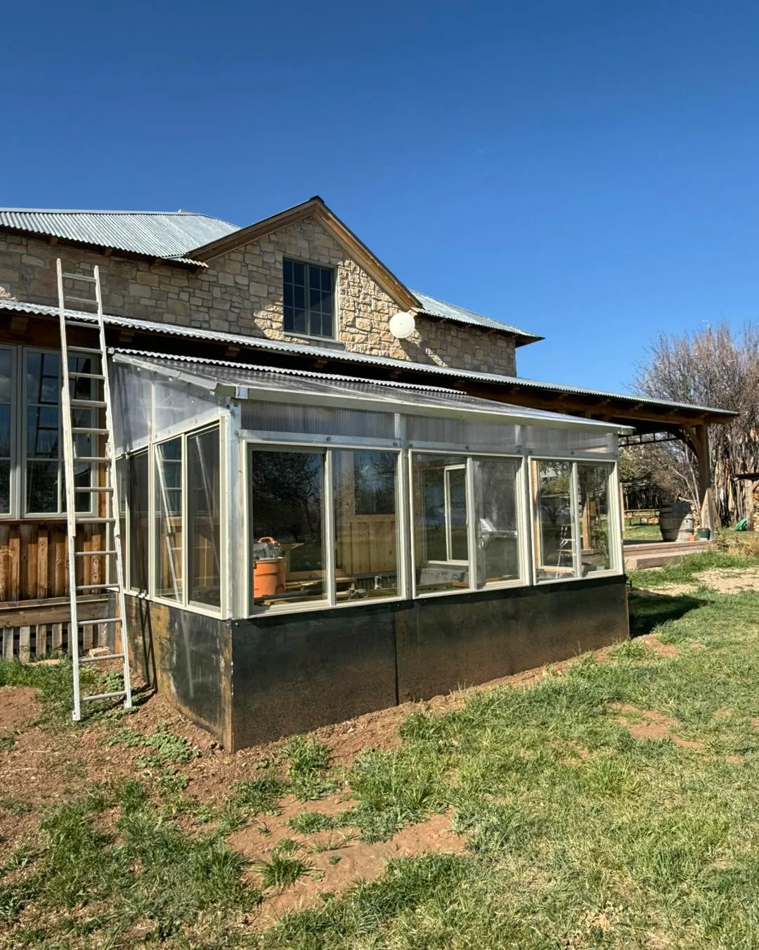 Custom metal frame greenhouse structure attached to stone building